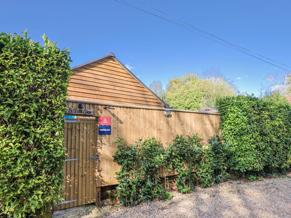 An outdoor view of Le Petit Glen in Uplyme with a wooden gate and hedges