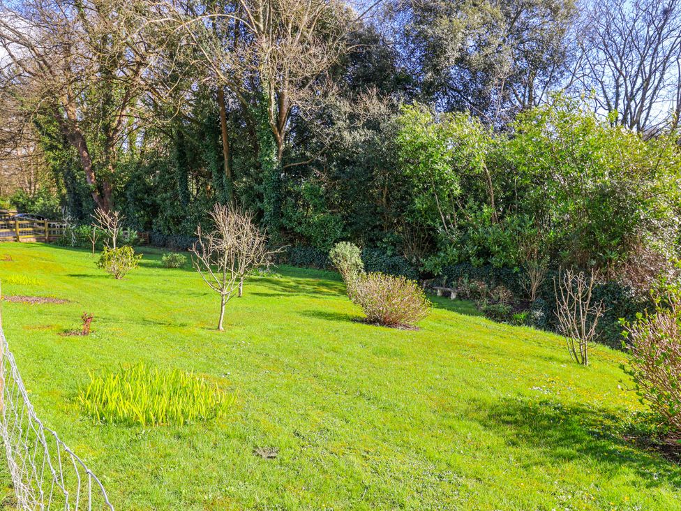 A garden with trees and flower beds at Le Petit Glen in Uplyme