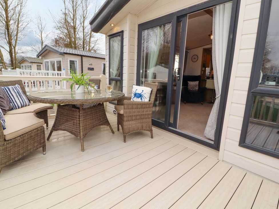 An outdoor seating area with a table and chairs at Hedgerow Lodge in Grange-Over-Sands