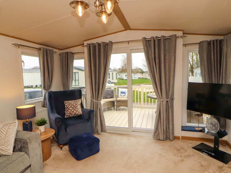 A living room with an armchair and television at Hedgerow Lodge in Grange-Over-Sands