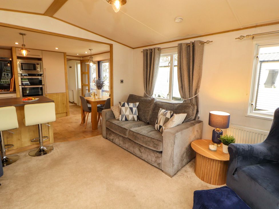 A living room with a sofa and dining area at Hedgerow Lodge in Grange-Over-Sands