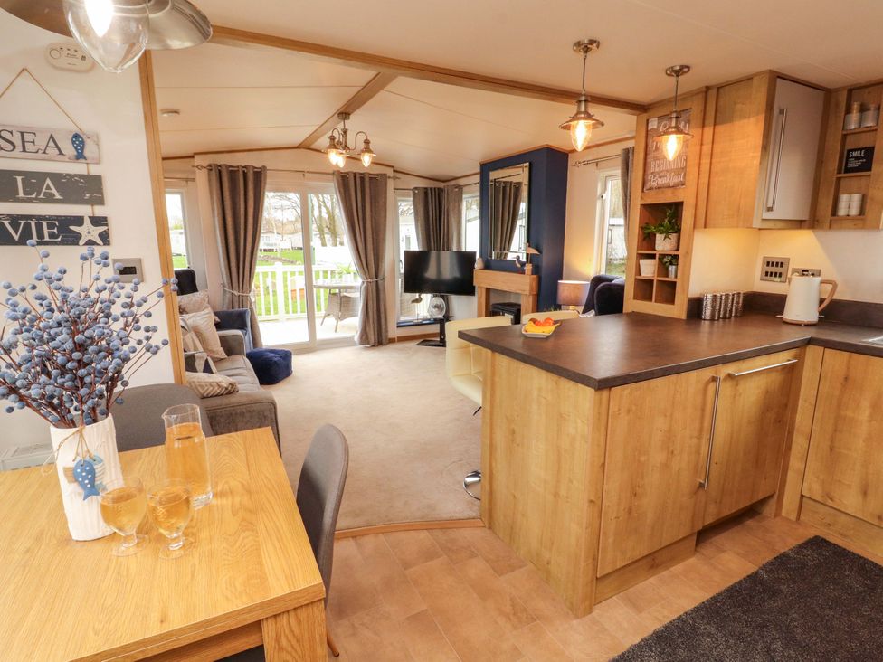 A living room with a kitchen area and dining table at Hedgerow Lodge in Grange-Over-Sands