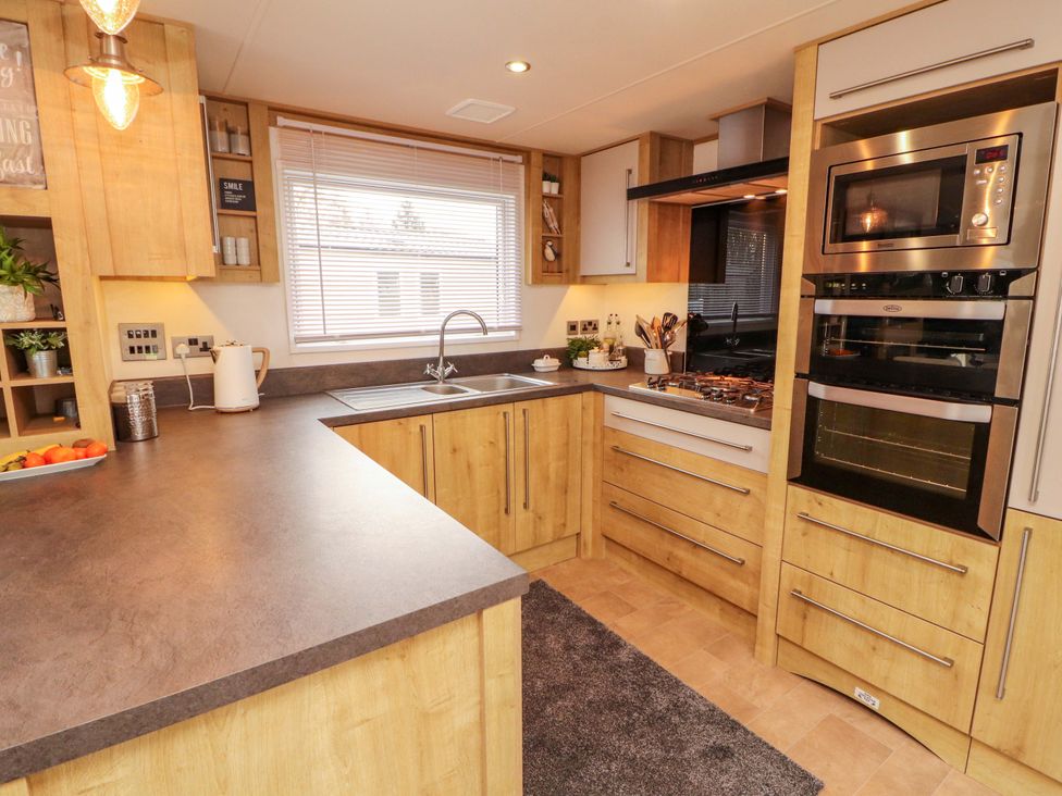A kitchen with cabinets and appliances at Hedgerow Lodge in Grange-Over-Sands