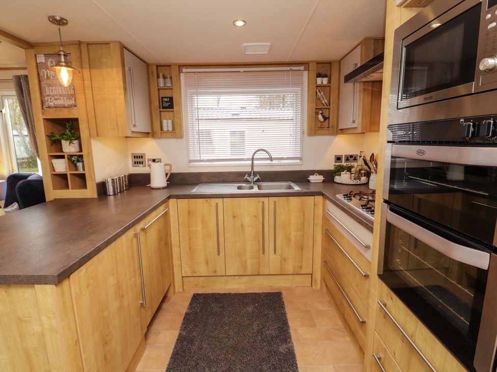A kitchen with cabinets, sink, and appliances at Hedgerow Lodge in Grange-Over-Sands