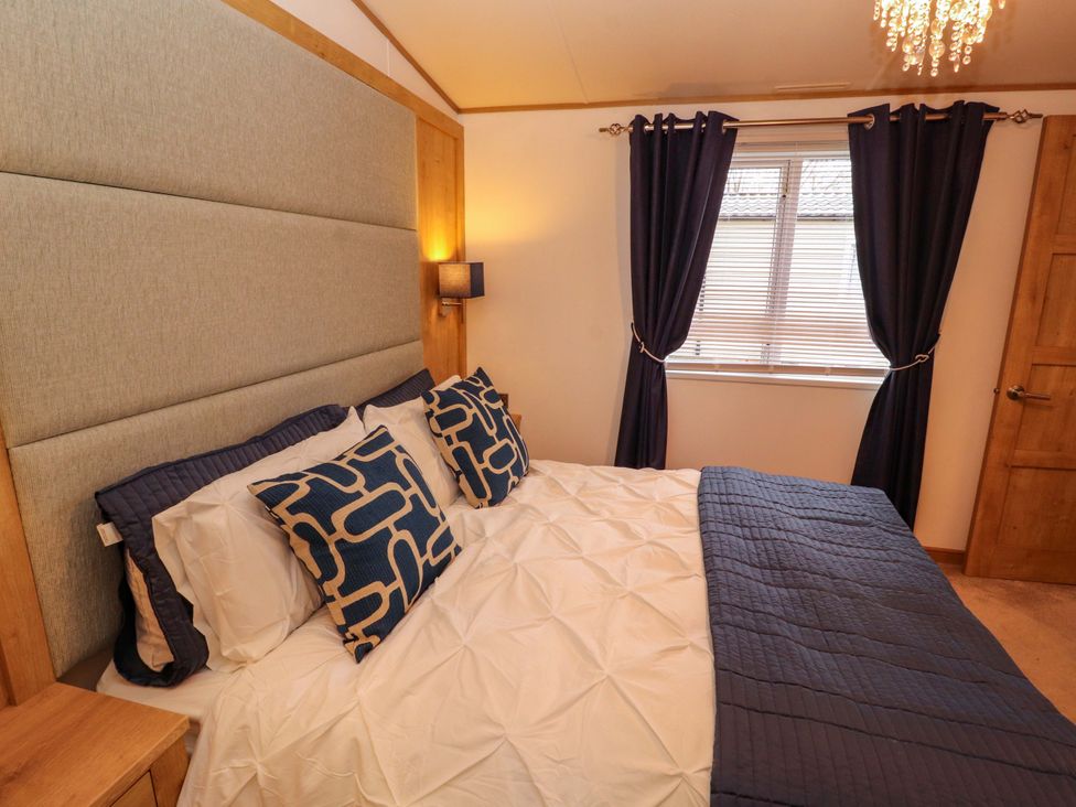A bedroom with a bed and decorative pillows at Hedgerow Lodge in Grange-Over-Sands