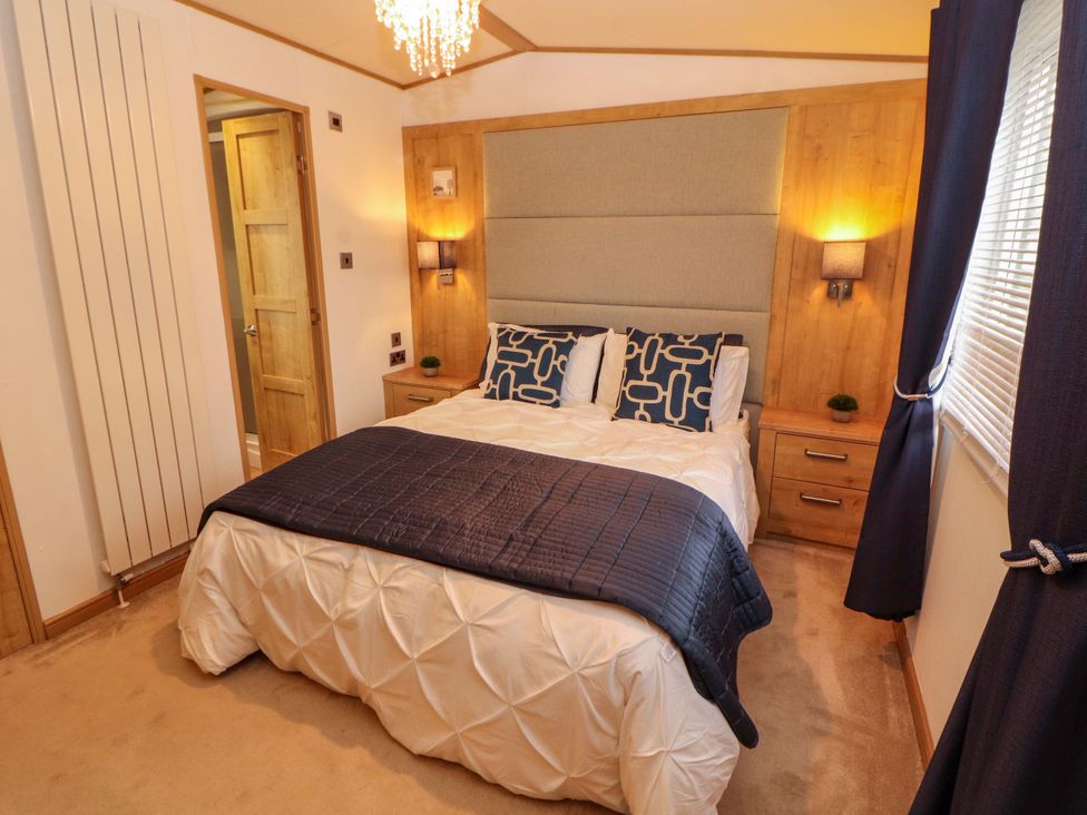 A bedroom with a bed and bedside table at Hedgerow Lodge in Grange-Over-Sands
