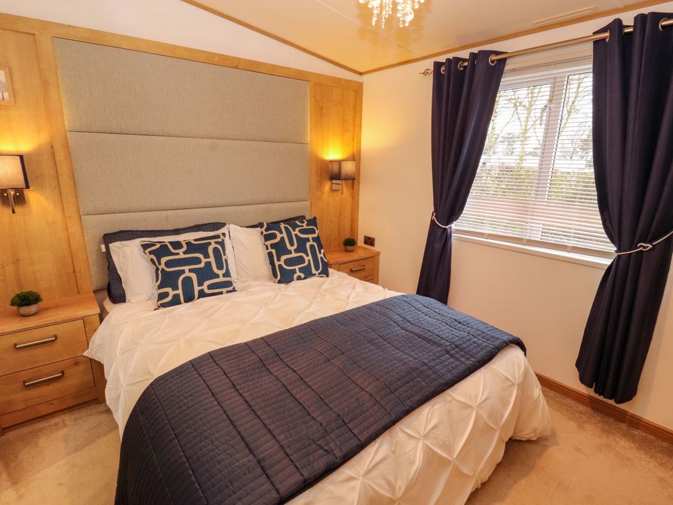 A bedroom with a bed and bedside tables at Hedgerow Lodge in Grange-Over-Sands