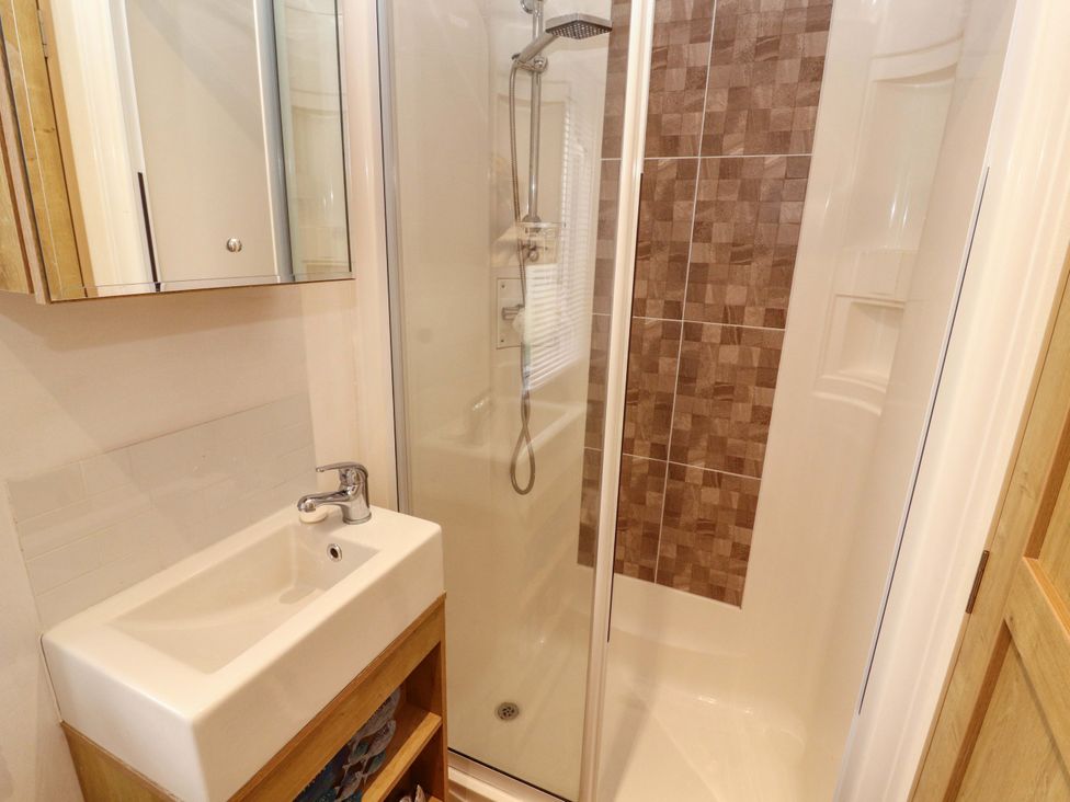 A bathroom with a shower and wash basin at Hedgerow Lodge Grange-Over-Sands