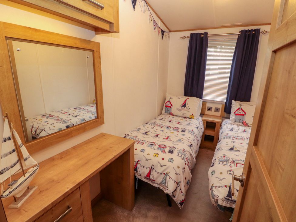 A bedroom with two single beds and a mirror at Hedgerow Lodge in Grange-Over-Sands