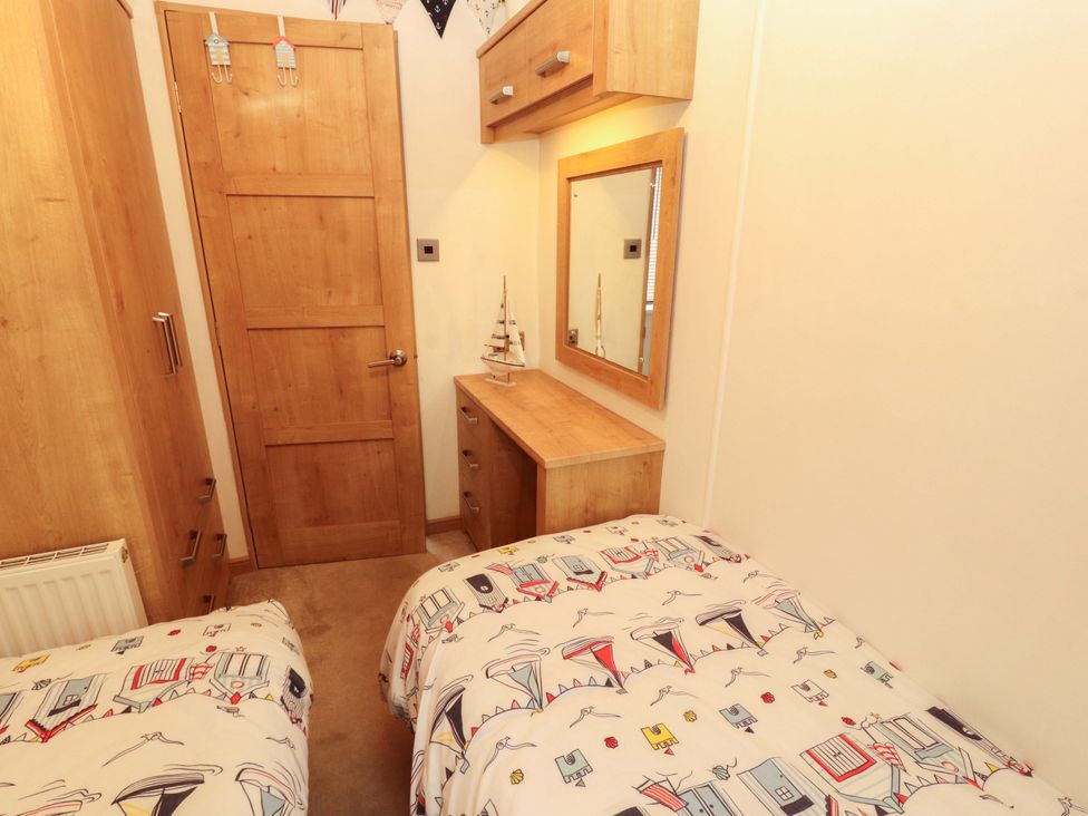 A bedroom with two beds and a wooden desk at Hedgerow Lodge Grange-Over-Sands
