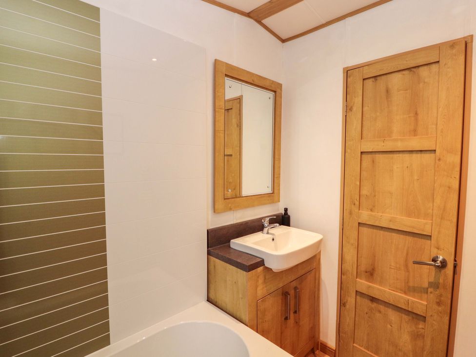 A bathroom with a sink and bathtub at Hedgerow Lodge in Grange-Over-Sands