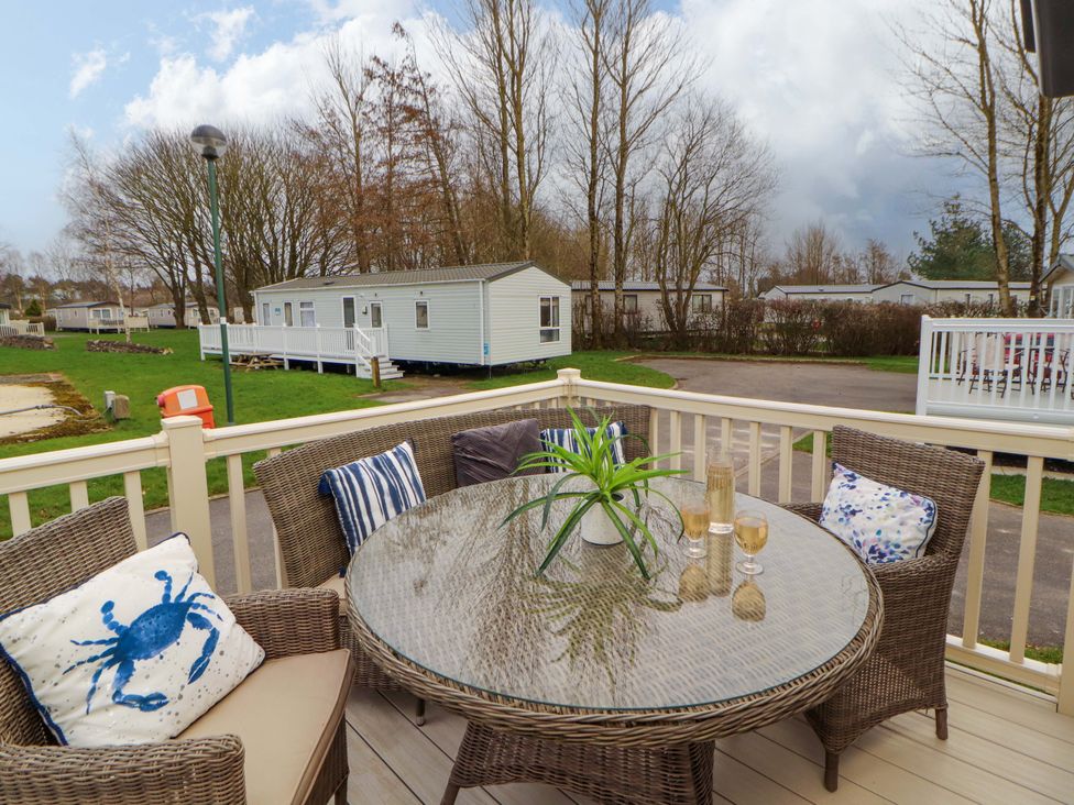 An outdoor seating area with a table and chairs at Hedgerow Lodge in Grange-Over-Sands