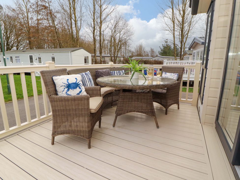 An outdoor seating area with a table and chairs at Hedgerow Lodge in Grange-Over-Sands
