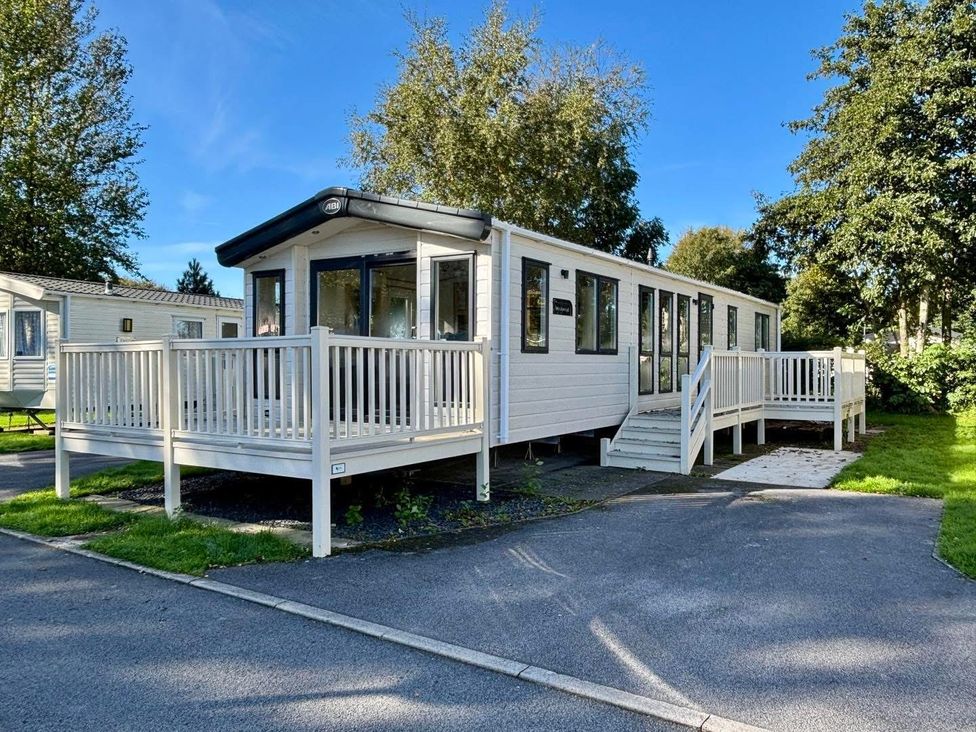 A mobile home with a deck and steps at Hedgerow Lodge near Haven Lakeside Grange-Over-Sands