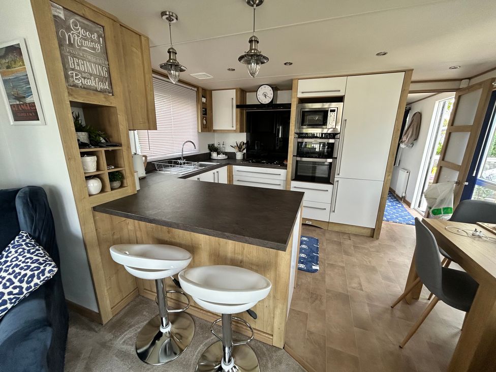 A kitchen with an island and stools at Hedgerow Lodge Haven Lakeside near Grange-Over-Sands