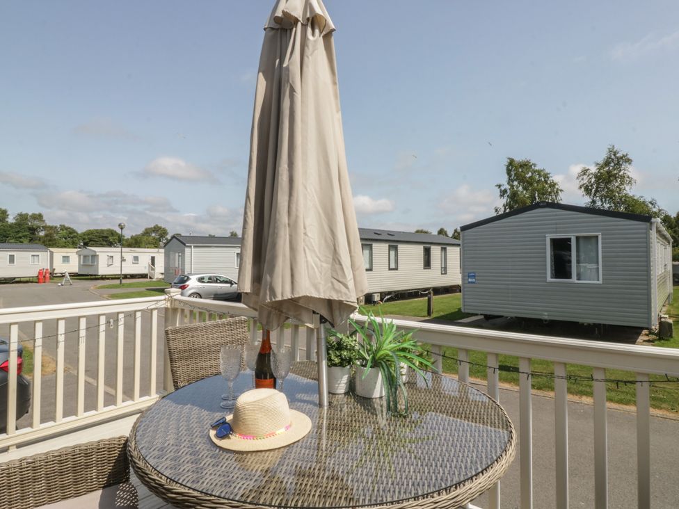An outdoor seating area with a table and umbrella at Hedgerow Lodge Haven Lakeside near Grange-Over-Sands