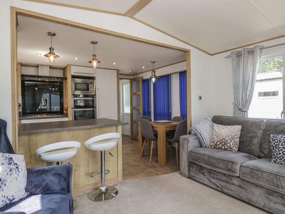 A living room with a sofa and dining area at Hedgerow Lodge in Haven Lakeside near Grange-Over-Sands