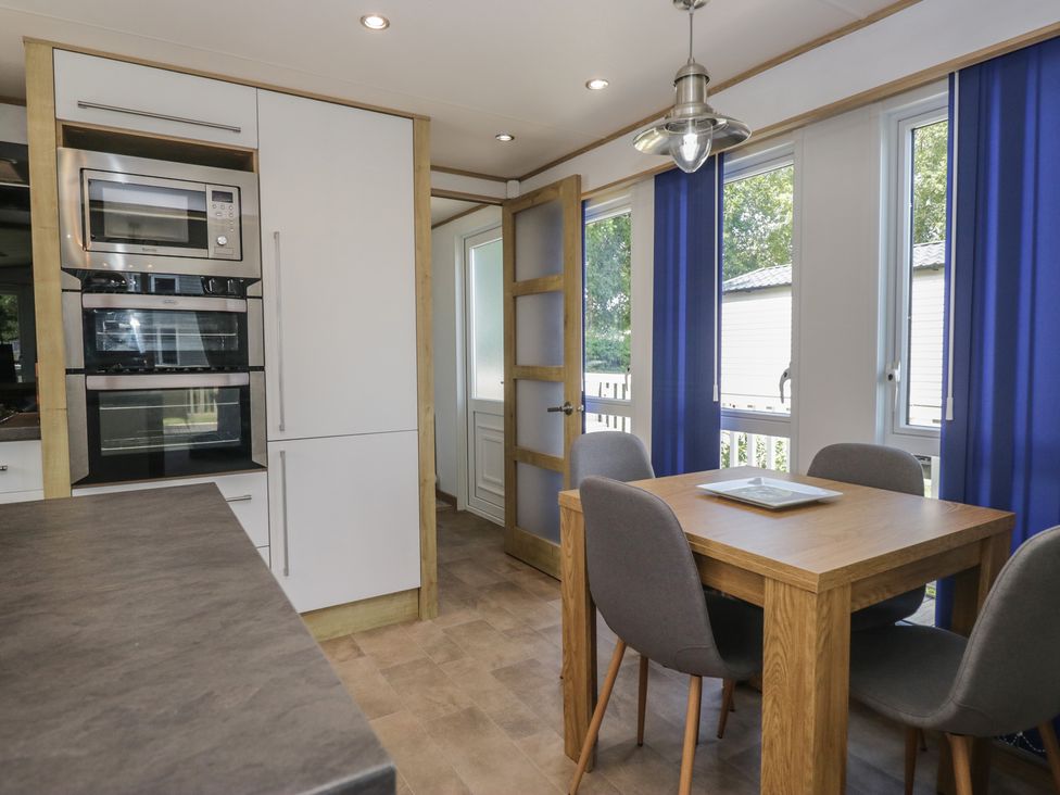A kitchen with appliances and dining area at Hedgerow Lodge near Haven Lakeside Grange-Over-Sands