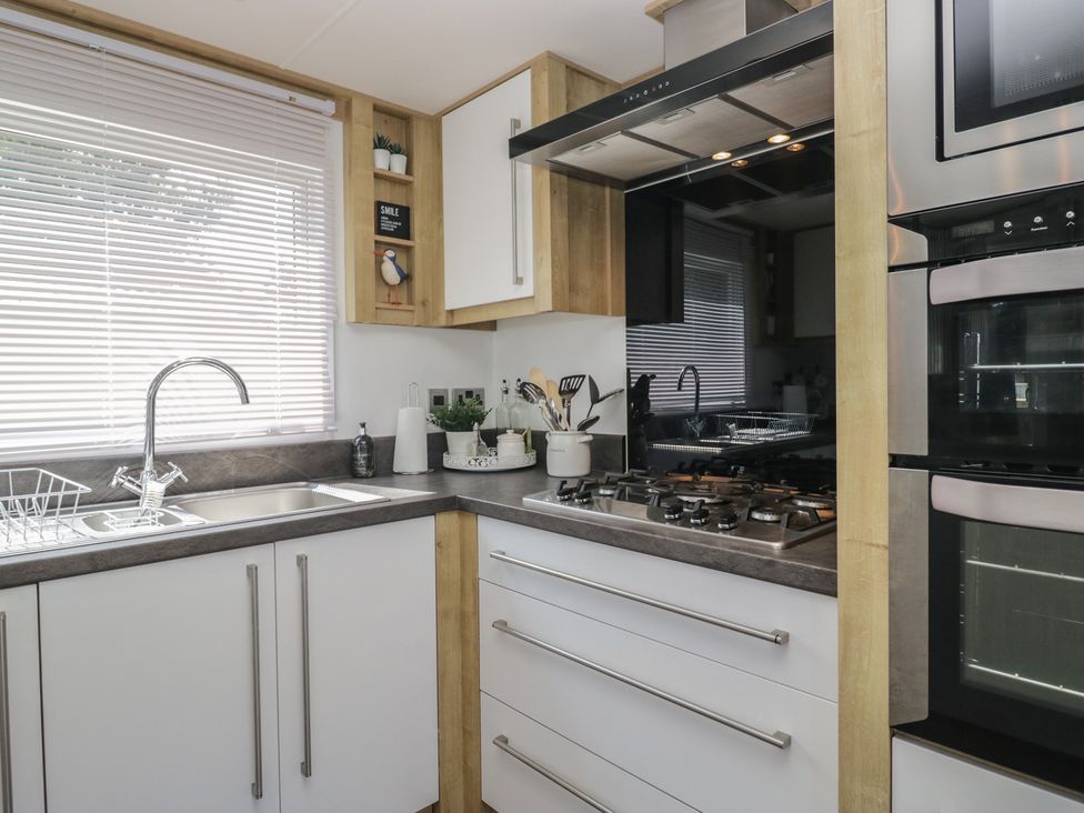 A kitchen with a sink and gas stove at Hedgerow Lodge near Haven Lakeside Grange-Over-Sands