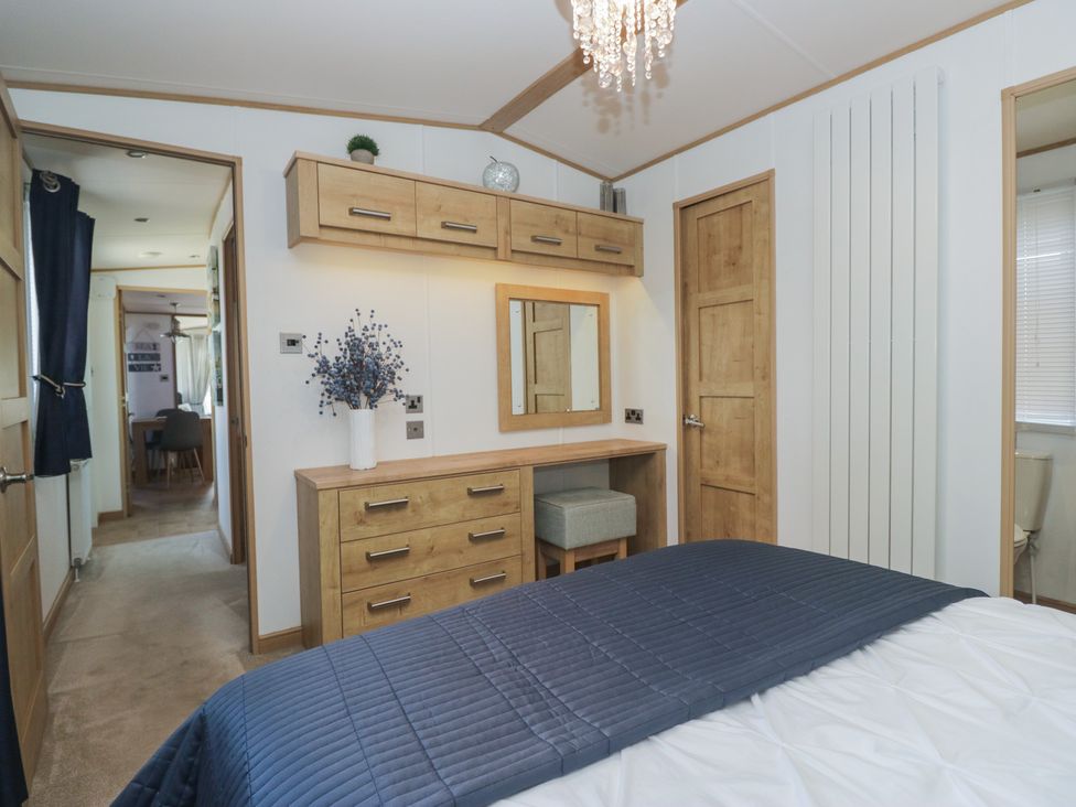 A bedroom with a dresser and mirror at Hedgerow Lodge Haven Lakeside near Grange-Over-Sands