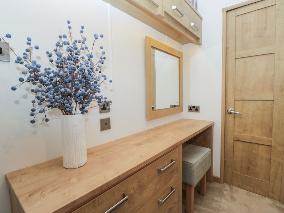 A bedroom with a dresser and a mirror at Hedgerow Lodge in Haven Lakeside near Grange-Over-Sands