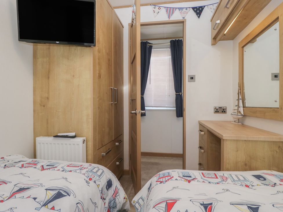 A bedroom with a wardrobe and television at Hedgerow Lodge near Haven Lakeside Grange-Over-Sands