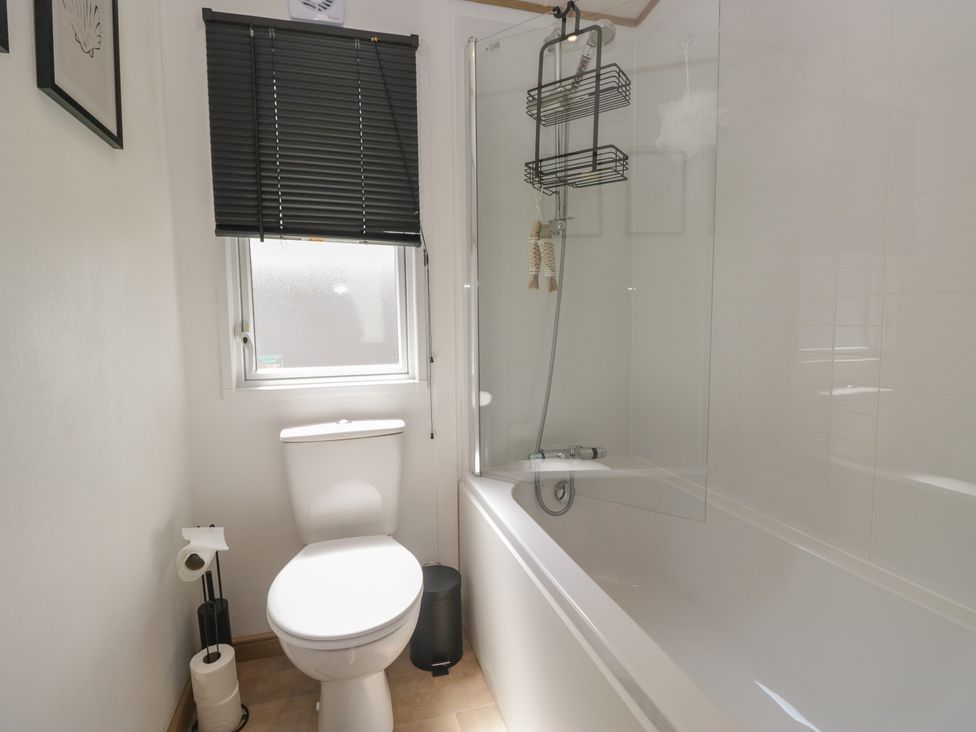 A bathroom with a toilet and a bathtub with a shower at Hedgerow Lodge near Haven Lakeside