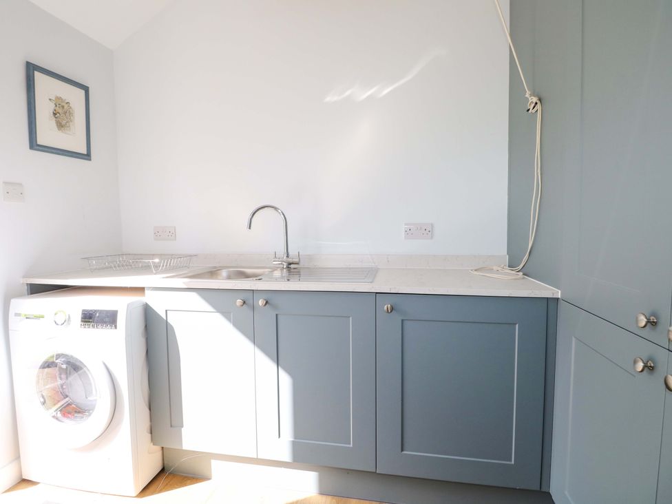 A laundry room with a washing machine and sink at Keepers Cottage in Petersfield