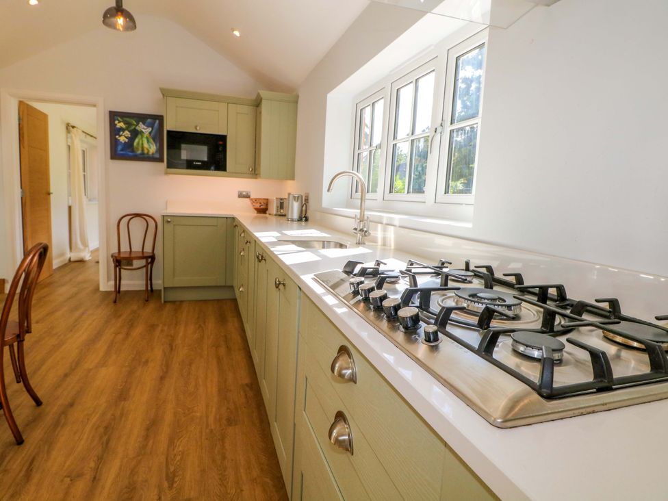 A kitchen featuring a gas stove and sink at Keepers Cottage in Petersfield