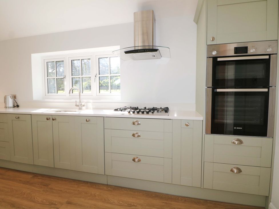 A kitchen with cabinets, sink, and oven at Keepers Cottage in Petersfield