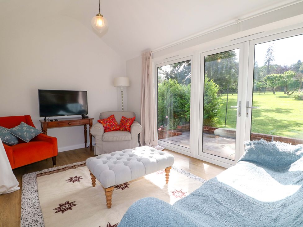 A living room with a television and coffee table at Keepers Cottage in Petersfield