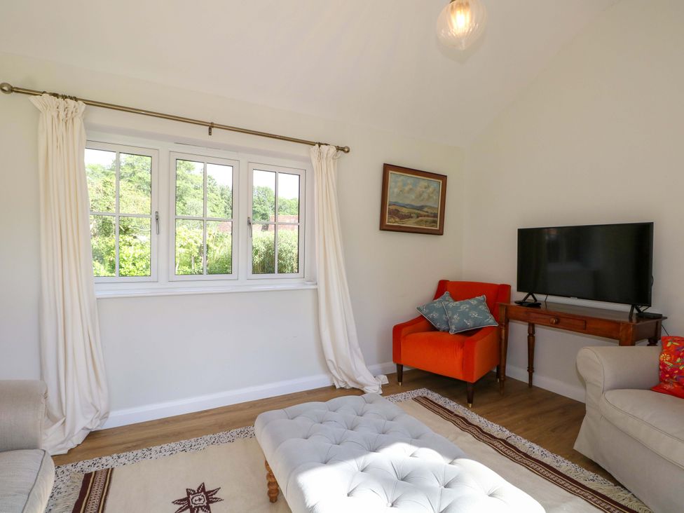 A living room with a television and a coffee table at Keepers Cottage in Petersfield