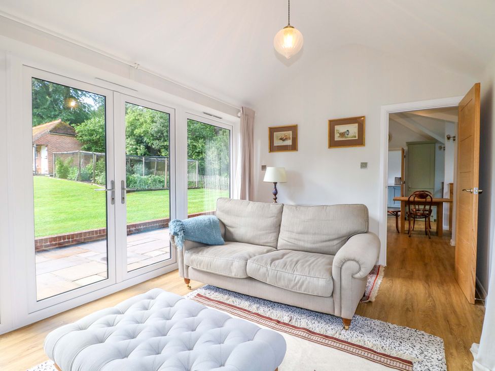 A living room with a sofa and ottoman at Keepers Cottage in Petersfield