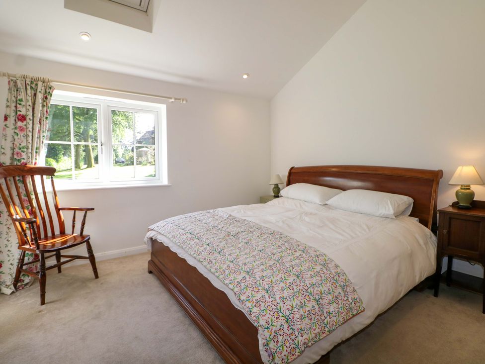 A bedroom with a bed and a chair at Keepers Cottage in Petersfield