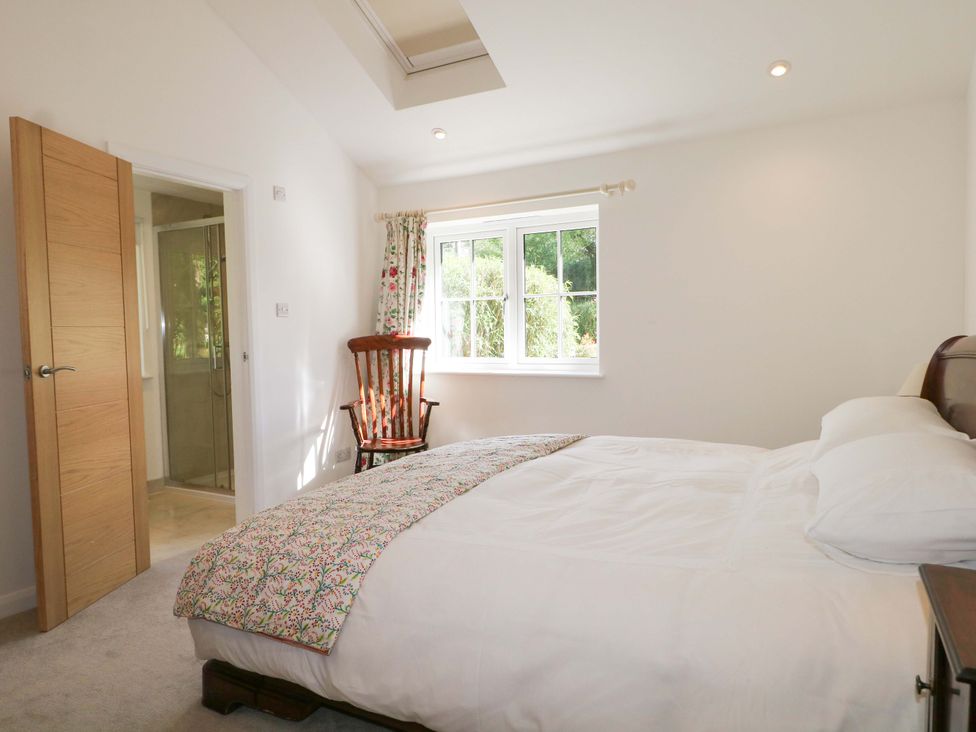 A bedroom with a bed and a chair at Keepers Cottage Petersfield