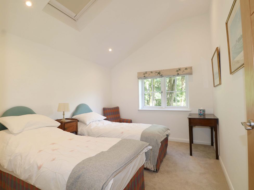 A bedroom with two beds and a window at Keepers Cottage in Petersfield