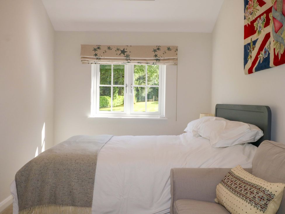 A bedroom with a bed and window at Keepers Cottage, Petersfield