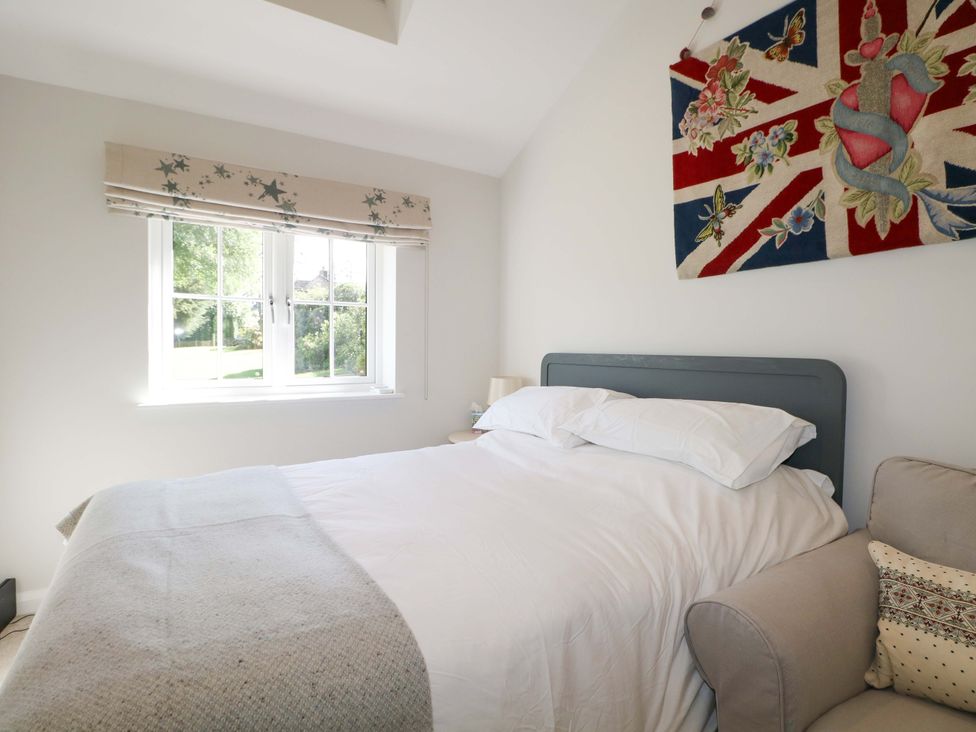 A bedroom with a bed and window at Keepers Cottage in Petersfield