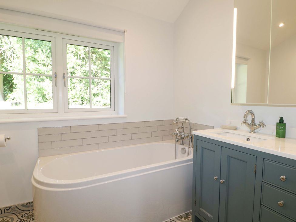 A bathroom with a bathtub and sink at Keepers Cottage in Petersfield