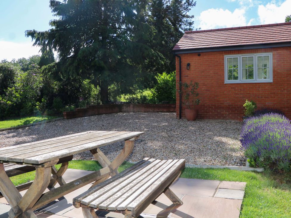 A patio area with a table and benches at Keepers Cottage Petersfield