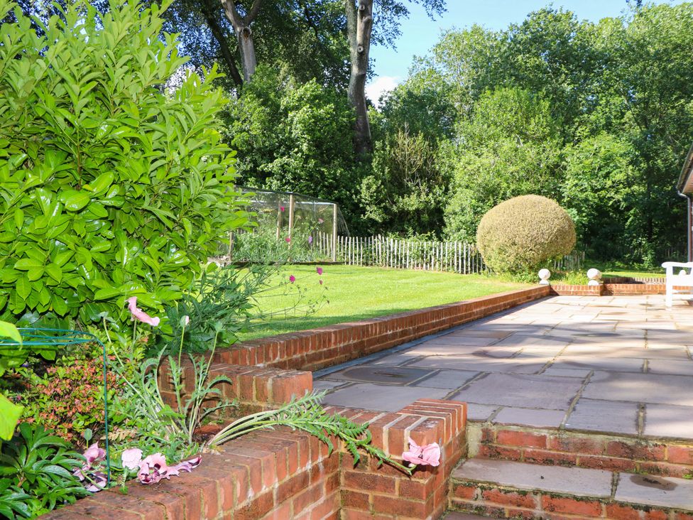 A garden with a stone patio and flowers at Keepers Cottage in Petersfield