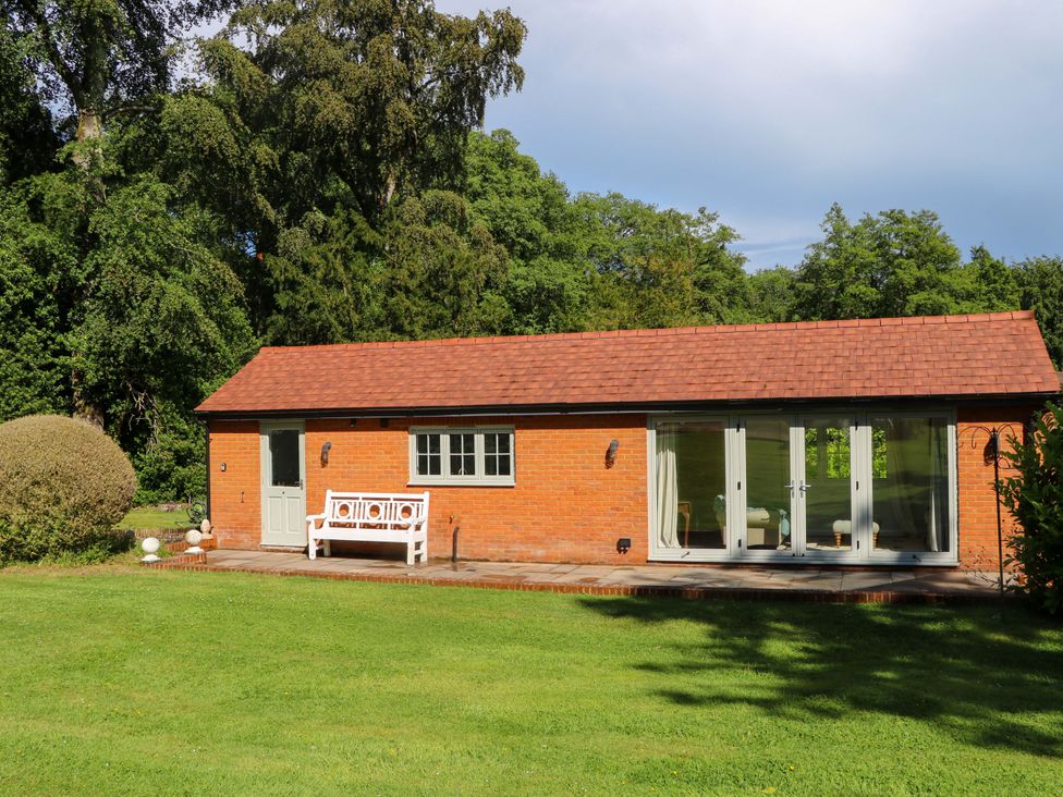 A house with a bench in front and garden at Keepers Cottage in Petersfield
