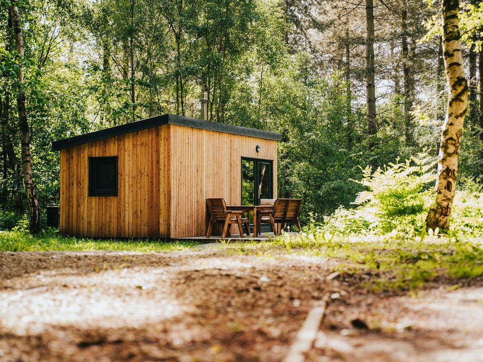 A wooden cabin with a table and chairs outside at Sherwood - Cosy Pod 3 Mansfield