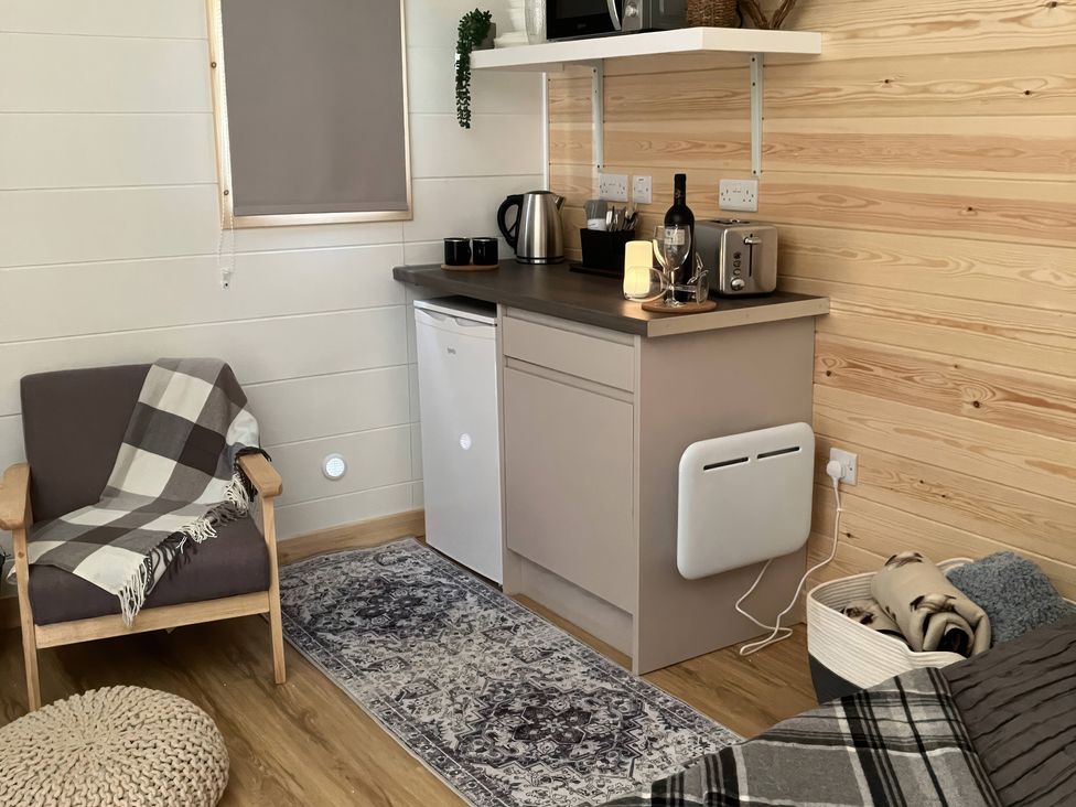 A kitchen area with a fridge, microwave, and a chair at Sherwood - Cosy Pod 4 in Mansfield