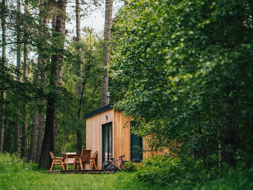A cabin with a table and chairs surrounded by trees at Sherwood - Cosy Pod 4 Mansfield