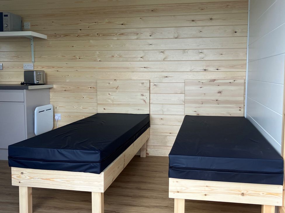 A bedroom with two beds and a shelf with a microwave at Sherwood - Cosy Pod 6 in Mansfield