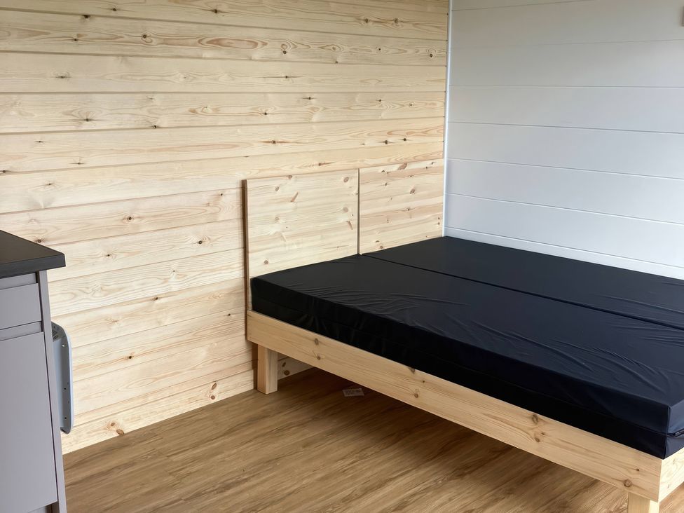A bedroom with a bed and wooden walls at Sherwood - Cosy Pod 6 in Mansfield