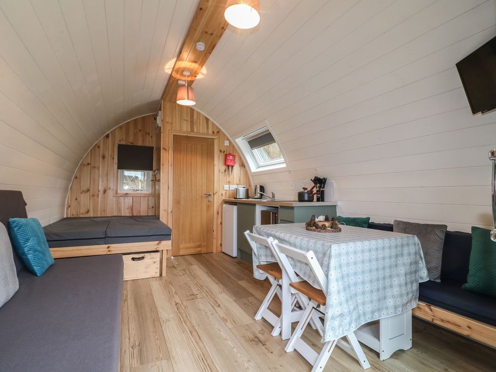 A living room with a sofa and kitchenette at Bracelands - Deluxe Pod 6 Coleford