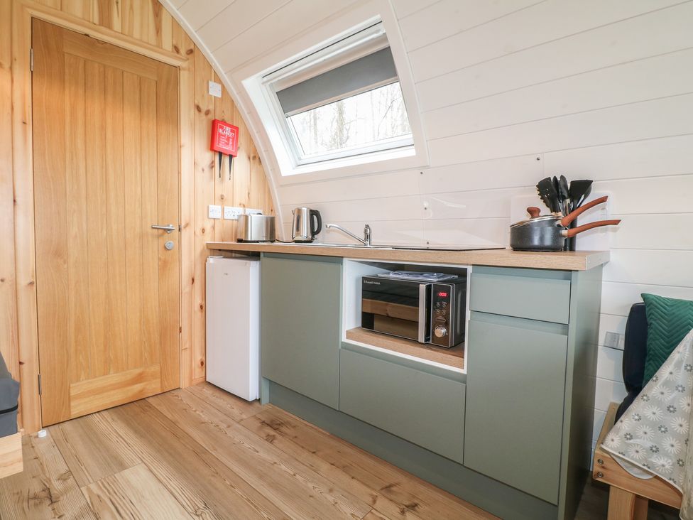 A kitchen with a door, fridge, microwave, and sink at Bracelands - Deluxe Pod 6, Coleford