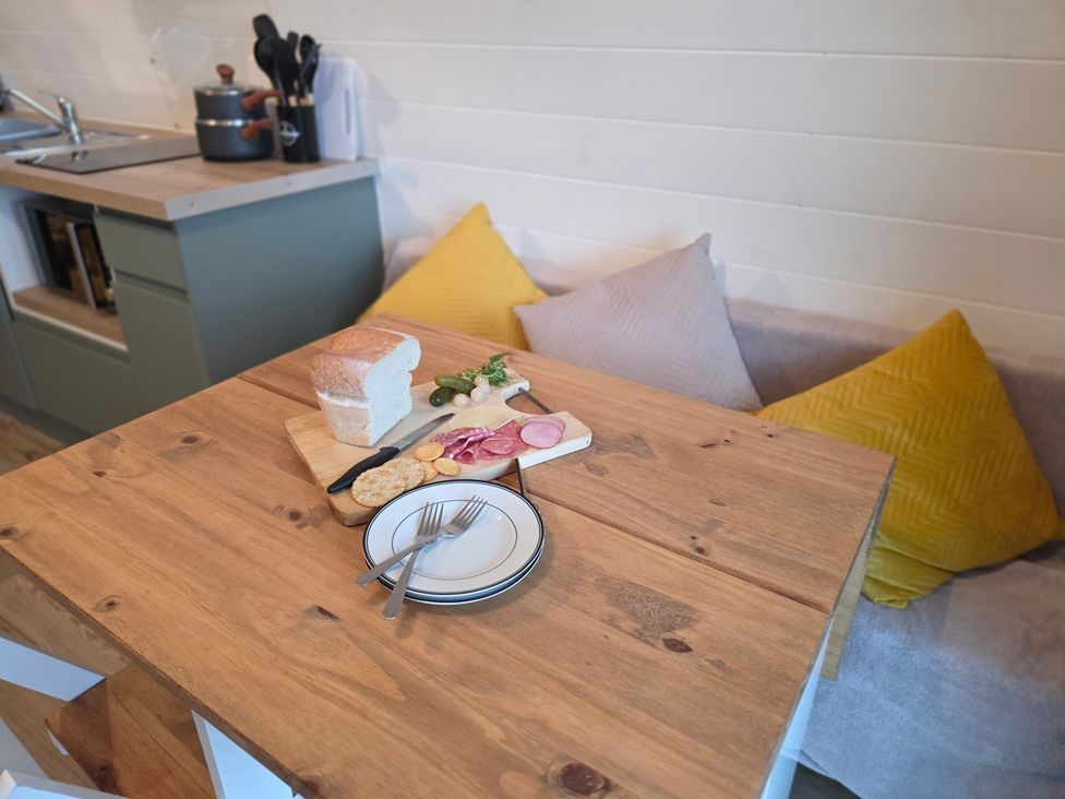 A kitchen with a dining table and food on a cutting board at Bracelands - Deluxe Pod 8, Coleford